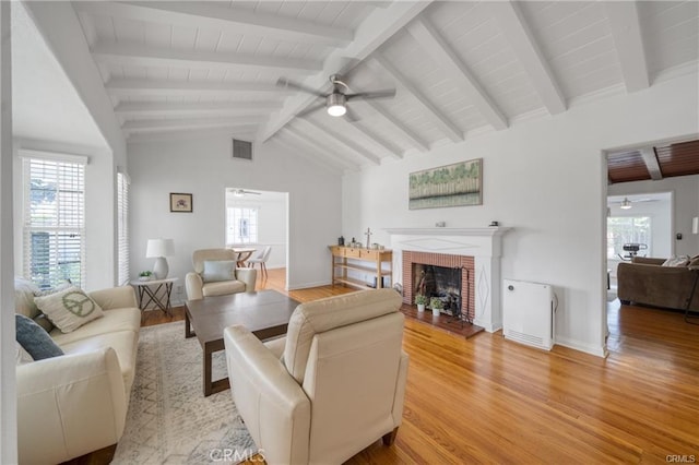 living room featuring lofted ceiling with beams, a ceiling fan, visible vents, and light wood-style floors