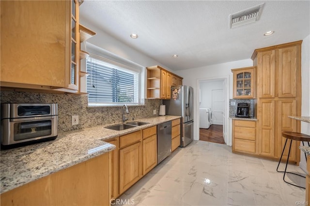 kitchen with marble finish floor, stainless steel appliances, visible vents, a sink, and separate washer and dryer