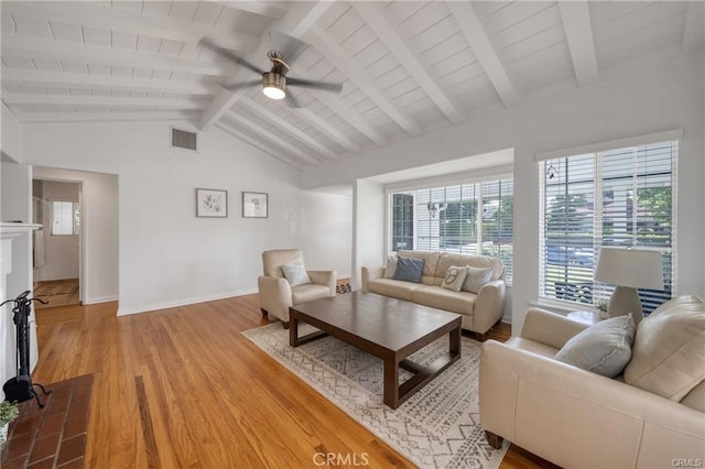 living room featuring lofted ceiling with beams, ceiling fan, visible vents, baseboards, and light wood finished floors