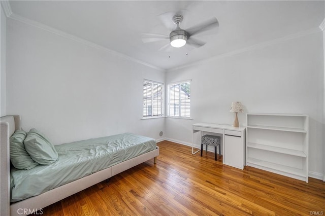 bedroom with baseboards, ornamental molding, a ceiling fan, and light wood-style floors