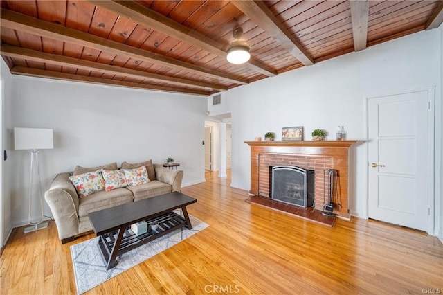 living area featuring light wood-type flooring, a brick fireplace, wood ceiling, and beam ceiling