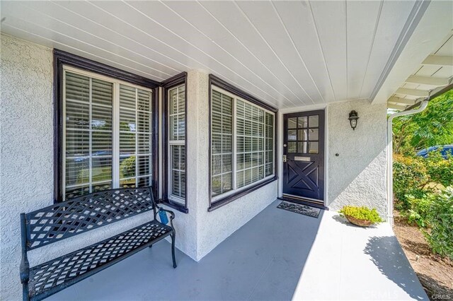 doorway to property with covered porch and stucco siding