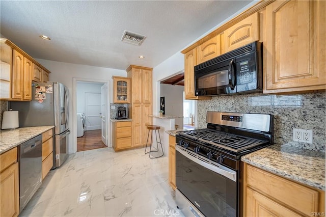 kitchen featuring washing machine and dryer, visible vents, marble finish floor, appliances with stainless steel finishes, and decorative backsplash