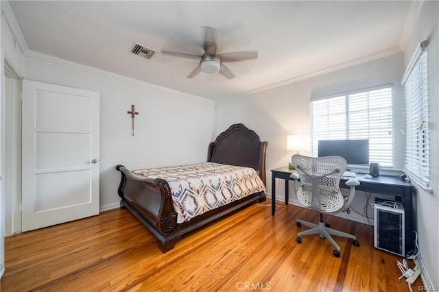 bedroom featuring ornamental molding, light wood finished floors, visible vents, and baseboards