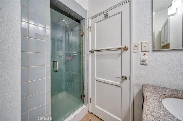 full bathroom with a textured wall, a shower stall, vanity, and tile patterned floors