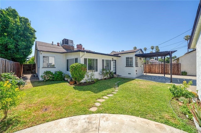 back of house with a fenced backyard, a chimney, a yard, a pergola, and stucco siding