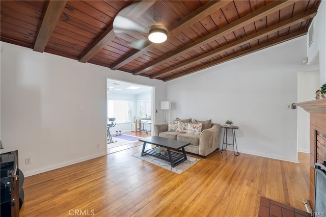 living area featuring light wood finished floors, wood ceiling, a fireplace, and baseboards