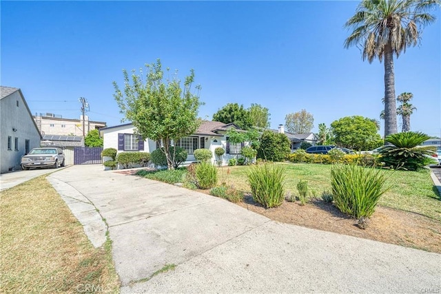 view of front facade with driveway, fence, and a front lawn