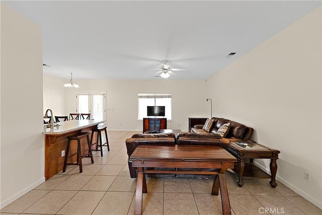 living room with ceiling fan with notable chandelier, visible vents, baseboards, and light tile patterned flooring