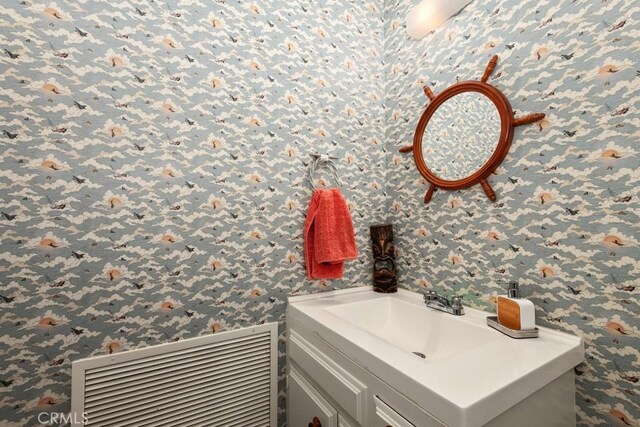 bathroom featuring vanity and wallpapered walls