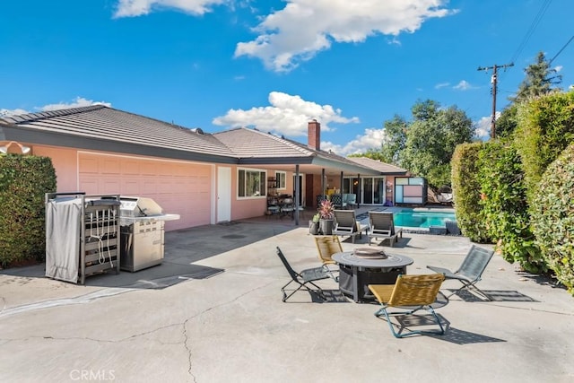 back of property featuring a garage, a fire pit, a patio, a tiled roof, and stucco siding