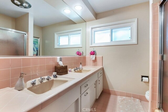 bathroom with a shower with door, tile patterned flooring, tasteful backsplash, and a sink