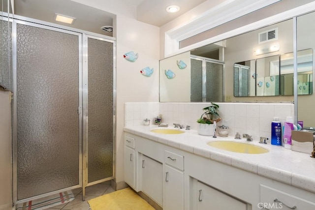 bathroom featuring tasteful backsplash, a stall shower, a sink, and visible vents