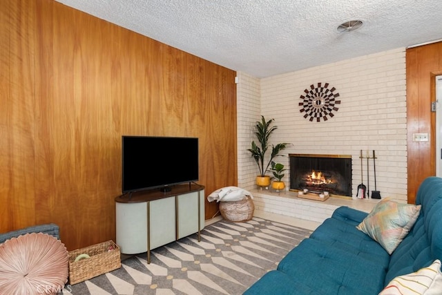 living room featuring wood walls, carpet, a fireplace, and a textured ceiling