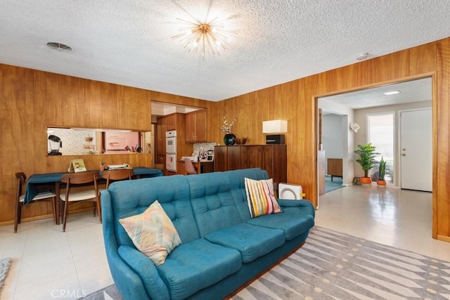 living area featuring wood walls, a textured ceiling, and an inviting chandelier