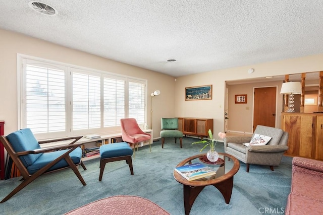 carpeted living area featuring a textured ceiling, visible vents, and baseboards