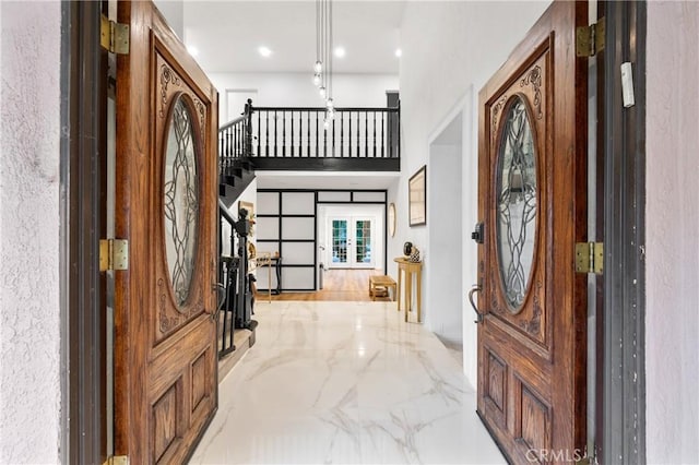 foyer entrance with marble finish floor, french doors, stairway, and a high ceiling