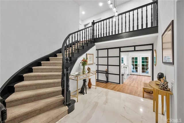 staircase featuring recessed lighting, french doors, marble finish floor, and a high ceiling