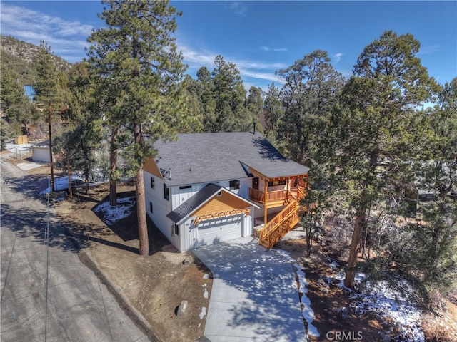 view of front of property with a shingled roof, driveway, and stairway