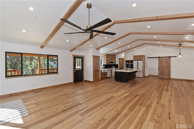 unfurnished living room featuring a ceiling fan, light wood-style floors, lofted ceiling with beams, and a barn door