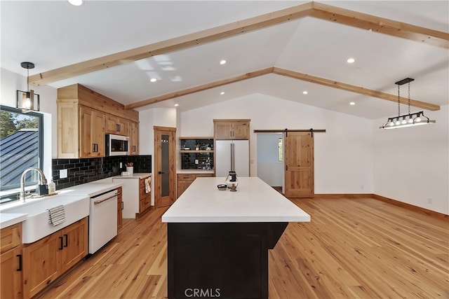 kitchen with stainless steel microwave, a barn door, white dishwasher, high quality fridge, and a sink