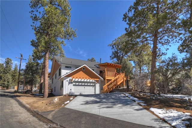 view of front of house featuring concrete driveway, stairway, board and batten siding, and an attached garage