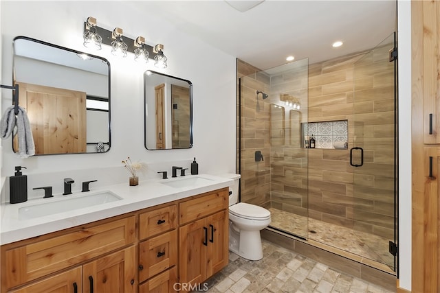 bathroom with double vanity, a sink, toilet, and a shower stall