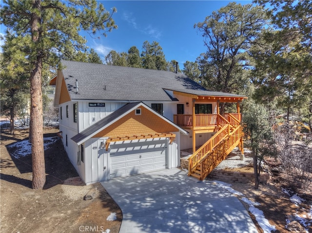 view of front facade featuring roof with shingles, concrete driveway, board and batten siding, a garage, and stairs