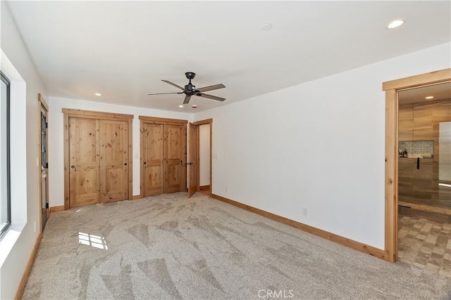 unfurnished bedroom with baseboards, connected bathroom, carpet flooring, multiple closets, and recessed lighting