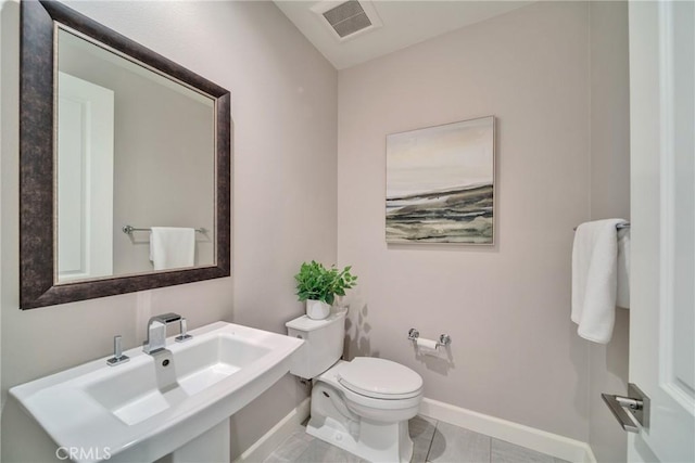 half bathroom with tile patterned flooring, toilet, a sink, visible vents, and baseboards