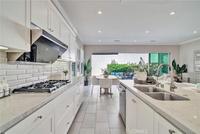 kitchen with a sink, white cabinets, appliances with stainless steel finishes, backsplash, and crown molding