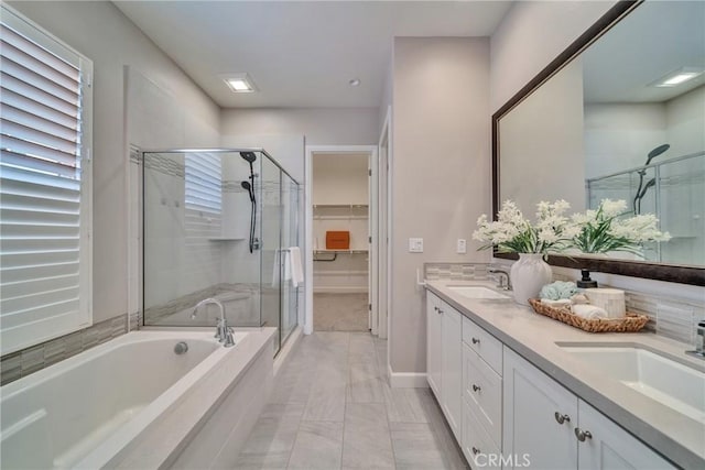 bathroom with a sink, a spacious closet, a shower stall, a bath, and double vanity