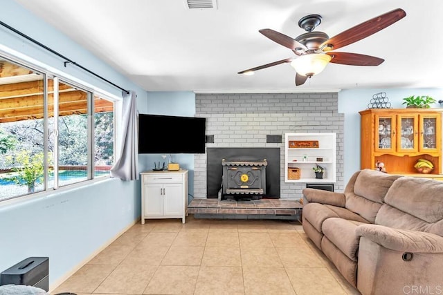 living area featuring light tile patterned floors, visible vents, a wood stove, and ceiling fan