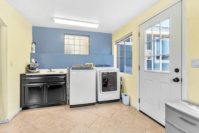 washroom with light tile patterned floors, cabinet space, a sink, and washing machine and clothes dryer