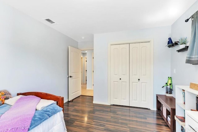 bedroom with visible vents, baseboards, a closet, and wood finished floors