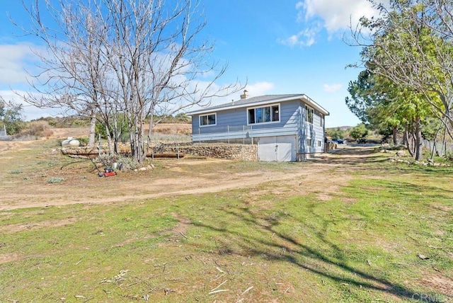 back of house with a lawn and dirt driveway