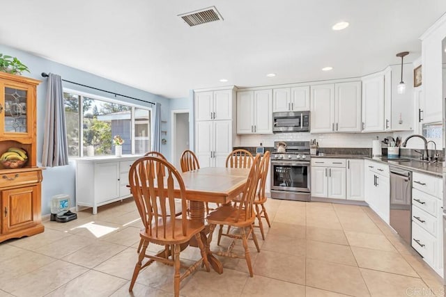 kitchen featuring tasteful backsplash, visible vents, light tile patterned floors, appliances with stainless steel finishes, and a sink