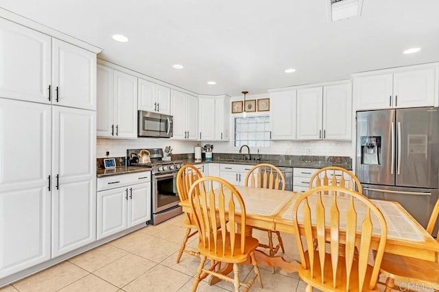 kitchen with light tile patterned floors, dark countertops, appliances with stainless steel finishes, and white cabinetry