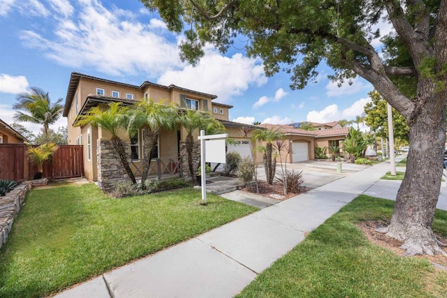 mediterranean / spanish-style house featuring a front yard, stucco siding, a garage, stone siding, and driveway