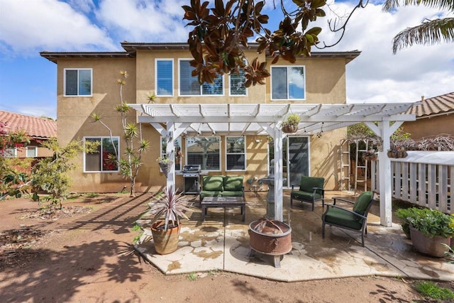 back of property with a patio area, stucco siding, a fire pit, and a pergola