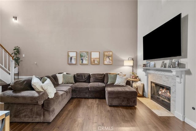 living area featuring a fireplace with flush hearth, stairs, a high ceiling, and dark wood finished floors