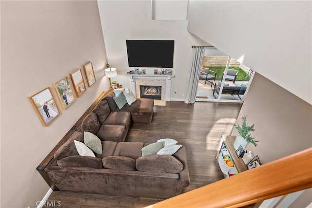 living room featuring a lit fireplace, wood finished floors, and baseboards