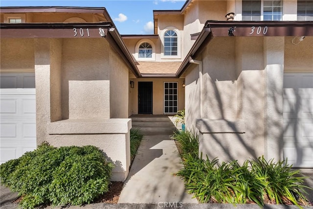 doorway to property featuring a garage and stucco siding