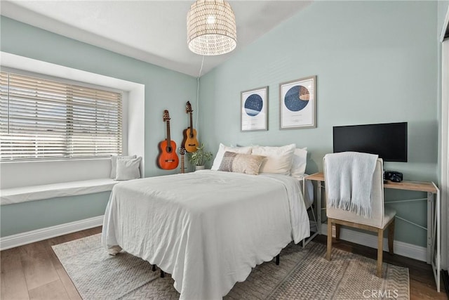 bedroom featuring vaulted ceiling, baseboards, and wood finished floors