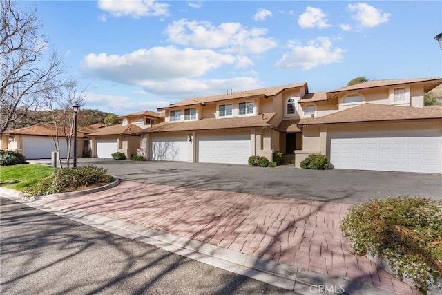 multi unit property with a garage, decorative driveway, and stucco siding