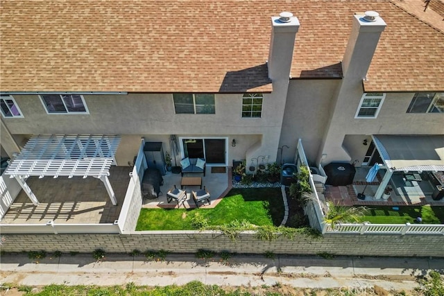 back of property featuring roof with shingles, fence, and stucco siding