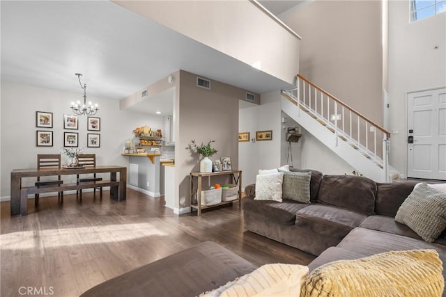 living area featuring a chandelier, visible vents, stairway, and wood finished floors