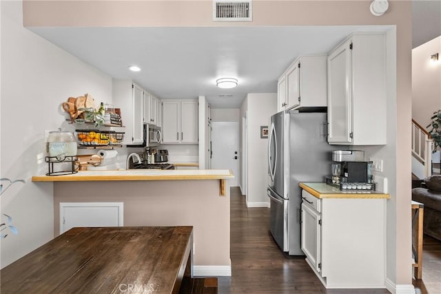 kitchen featuring appliances with stainless steel finishes, light countertops, white cabinets, and visible vents