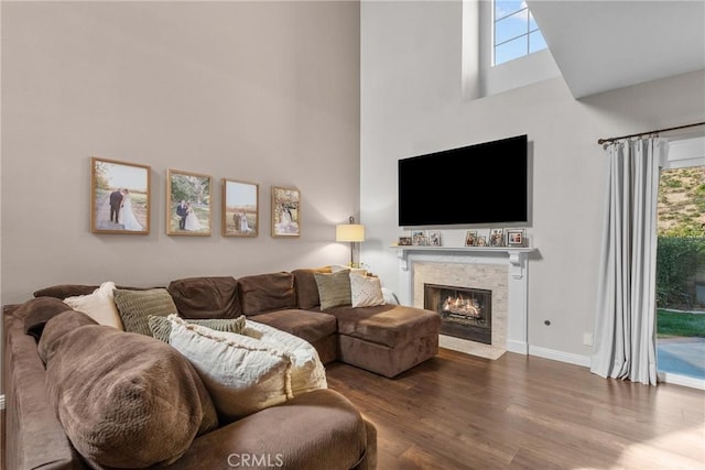 living area with a fireplace with flush hearth, a high ceiling, wood finished floors, and a wealth of natural light