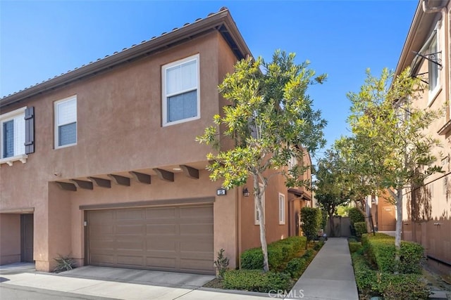 view of side of property with an attached garage, fence, and stucco siding